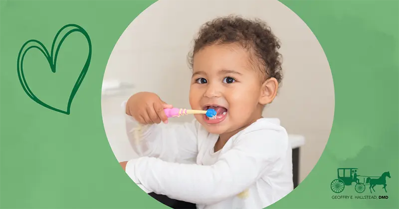 Young child in white bathrobe smiling while brushing teeth